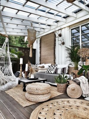 Create a vibrant bohemian patio with layered rugs, mixed seating, hanging plants, colorful lights, boho textiles, vintage decor, and low tables.